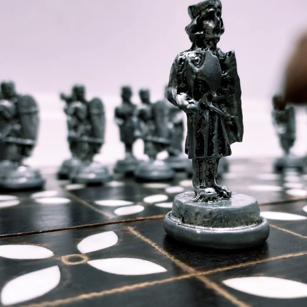 Pawn's-eye view: a pewter chess piece in sharp focus with the rest of the board blurred behind it